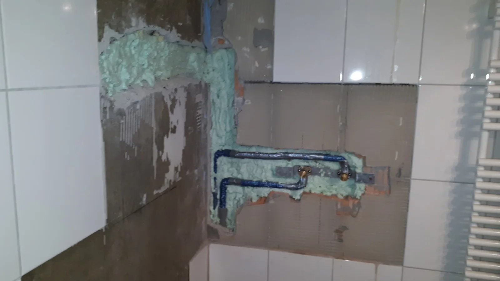 Vorwandinstallation im Bad: Armaturenanschlüsse in der Dämmung, die Wand ist teilweise gefliest